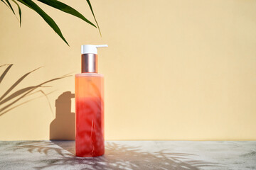 Empty bottle for cosmetics, shampoo, lotion or sunscreen. Cosmetic bottle in the bright rays of the sun and the shadow of palm leaves