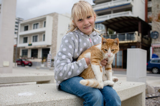 Little girl and street cat in the town