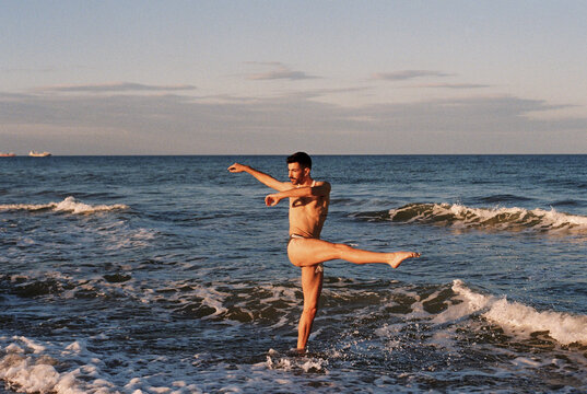 Male ballet dancer posing on the beach at sunset