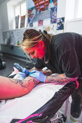 professional tattoo artist working in her studio with pleasure, loving job, vertical shot. High quality photo