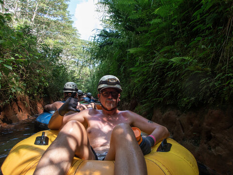 A man tubbing in a river making the shaka hand signal
