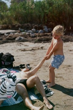 a kid drag his uncle to swim in a beach
