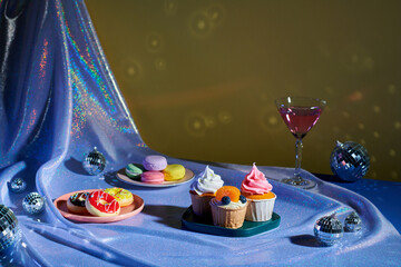 Tasty cupcakes, glasses of drink  on table in room