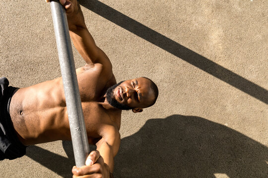 A young man pulls himself up on a horizontal bar on the workout area.