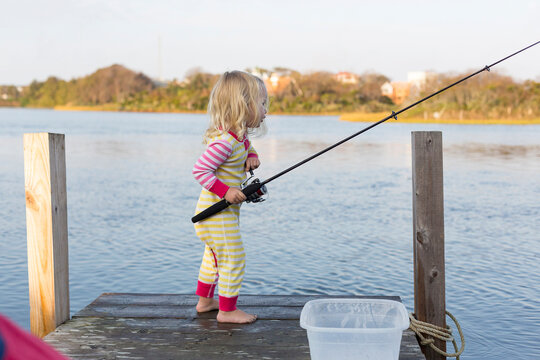 Young toddler fishing off dock at lake