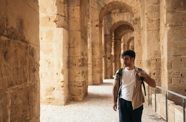 Backpacker man visiting El Djem roman amphitheater in Tunisia