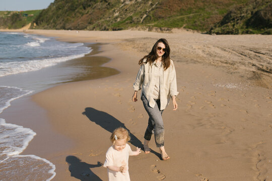 Mother and daughter walking by the coastline