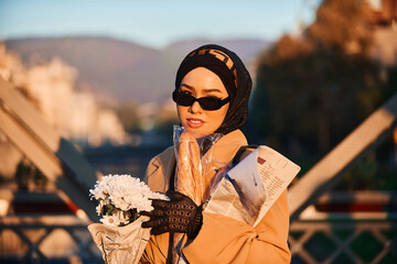 A hijab woman in stylish sunglasses and an elegant French outfit, walking through the city at...