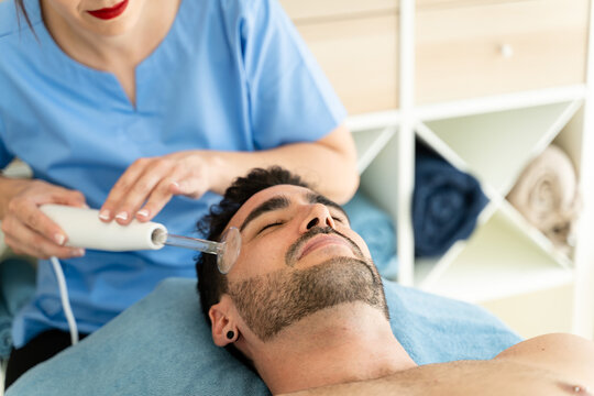 Female masseuse using high frequency device on male patient.