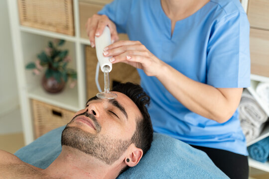 Female masseuse using high frequency device on male patient.