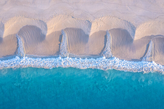 Aerial view of turquoise ocean creating patterns in the sand