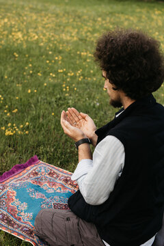 man raising hand in prayer in nature