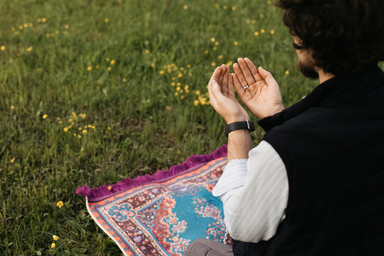man raising hand in prayer in nature