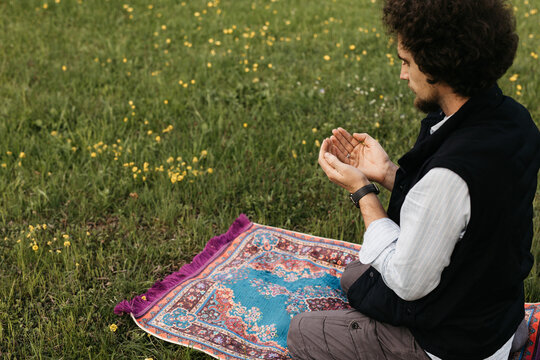 man raising hand in prayer in nature