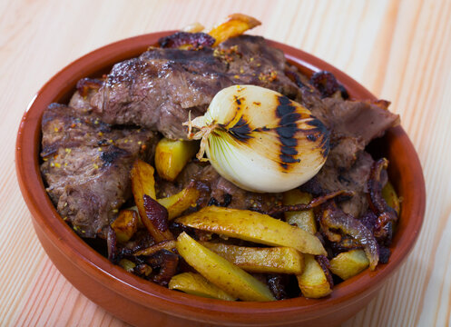 Navy-style beef (Sjomansbiff) with potatoes and onion in clay bowl on wooden table. Norwegian cuisine