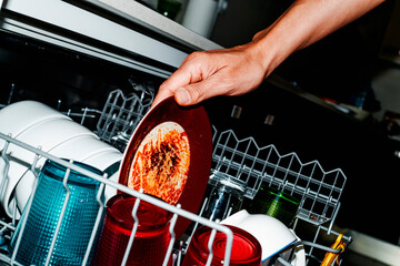man puts a dirty dish in the dishwasher