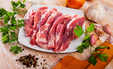 Preparation of raw turkey thigh with parsley and garlic on wooden cutting board