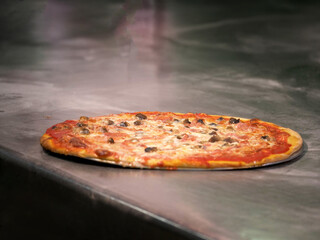 pizza margherita appena uscita dal forno su di una base di acciaio di una pizzeria