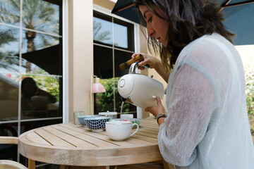 A woman pouring hot water into a mug