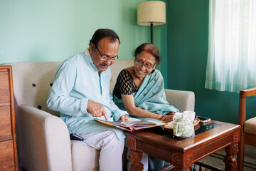 Senior couple browsing through old photo album having morning tea