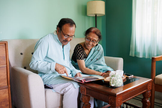 Senior couple browsing through old photo album having morning tea