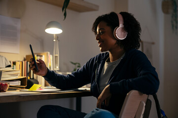 Teenage female in headphones using smartphone at home