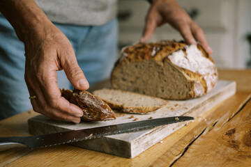 woman cutting fresh baked sourdough bread loaf
