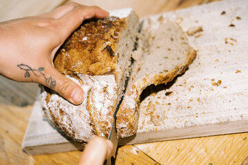 ugc pov of woman cutting fresh baked sourdough bread loaf