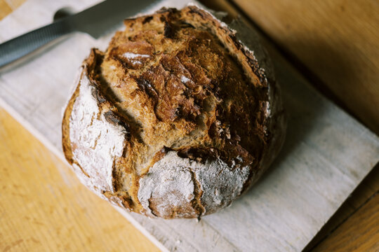 close up of a flour crusted sourdough bread loaf on cutting board