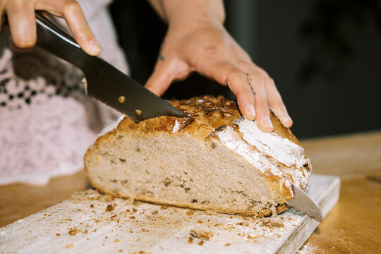 woman cutting fresh baked sourdough bread loaf