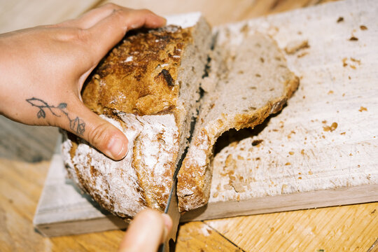 ugc pov of woman cutting fresh baked sourdough bread loaf