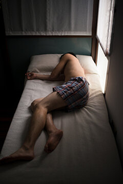 Depressed young man lying on bed 