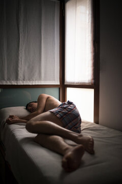 Young man feeling sad lying on bed