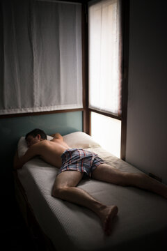 Young man sleeping on bed in underpants 