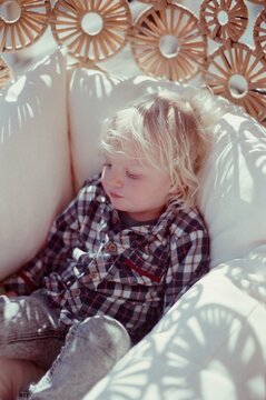 A kid in armchair in a shadow