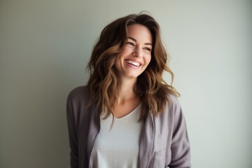 Obraz premium Lifestyle portrait photography of a grinning woman in her 30s wearing a chic cardigan against a minimalist or empty room background
