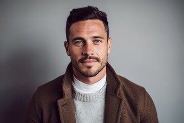 Obraz premium Portrait of a handsome young man looking at camera while standing against grey background