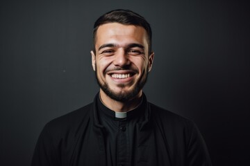 Portrait of a young smiling catholic priest on a dark background