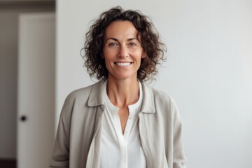 Fototapeta premium Portrait of smiling mature businesswoman standing against white wall at office