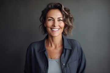 Fototapeta premium Portrait of a beautiful middle aged woman smiling at the camera on gray background