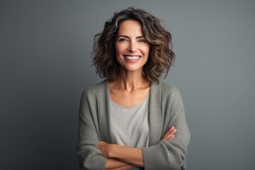 Obraz premium Portrait of a happy mature woman with arms crossed against grey background