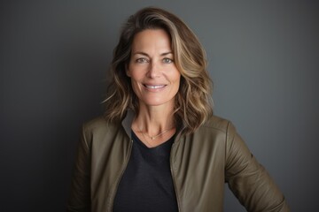 Fototapeta premium Portrait of beautiful middle aged woman smiling at the camera against grey background