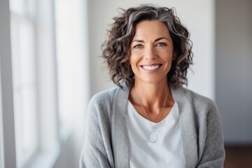 Portrait of beautiful mature woman with curly hair smiling at camera at home