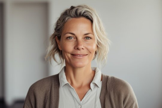 Close-up portrait photography of a pleased woman in her 40s wearing a chic cardigan against a minimalist or empty room background