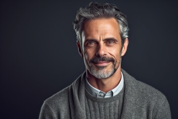 Handsome mature man looking at camera and smiling while standing against grey background