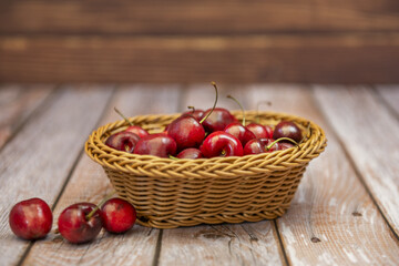 Delicious ripe cherries inside a small wicker basket on a wooden