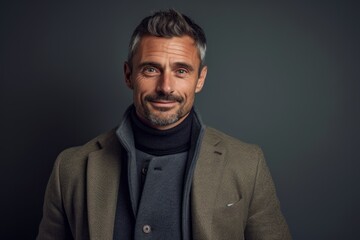 Obraz premium Portrait of handsome mature man in coat and scarf looking at camera isolated on grey background
