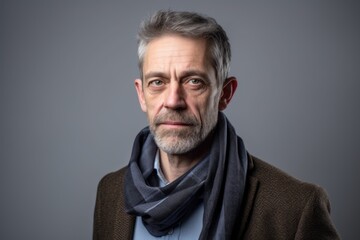 Portrait of a senior man with grey hair wearing a scarf.