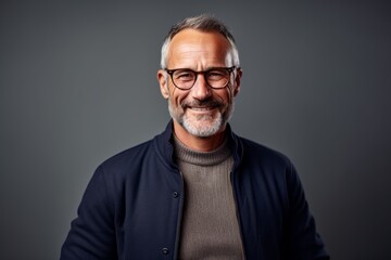 Obraz premium Smiling mature man in eyeglasses looking at camera on grey background