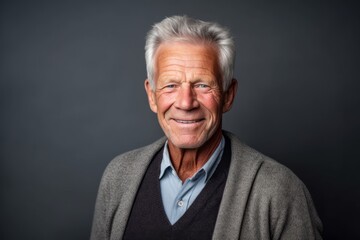 Portrait of a happy senior man on a dark background. Looking at camera.